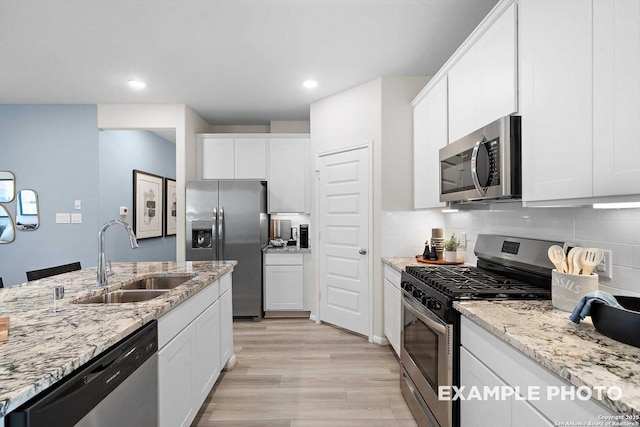 kitchen featuring stainless steel appliances, white cabinetry, a sink, and tasteful backsplash