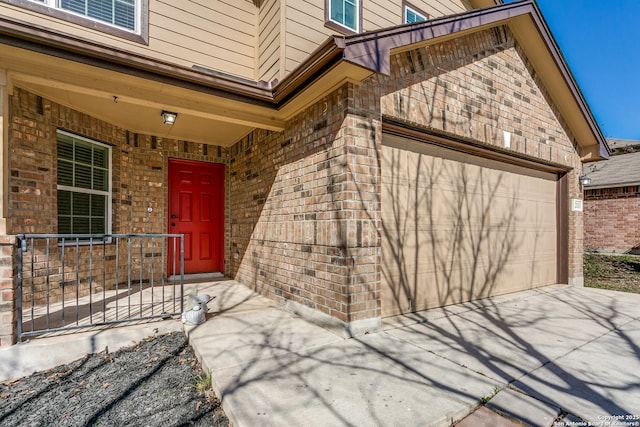 view of exterior entry featuring an attached garage and brick siding