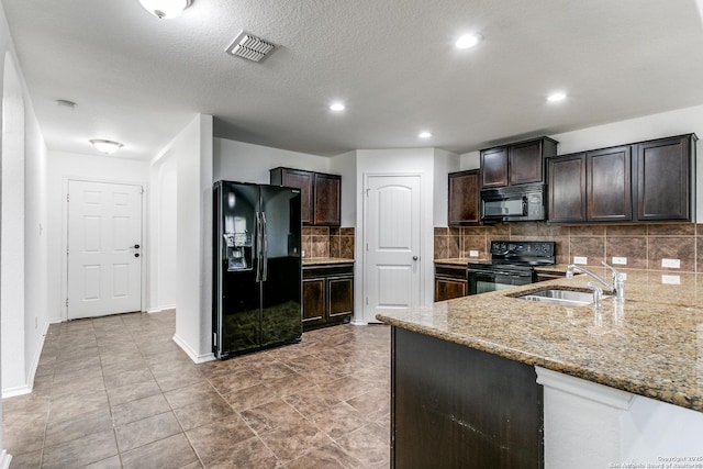 kitchen with light stone countertops, visible vents, a sink, black appliances, and backsplash