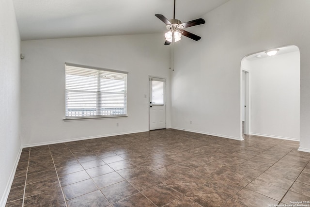 empty room featuring high vaulted ceiling, baseboards, arched walkways, and ceiling fan