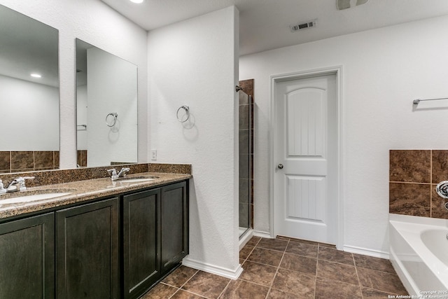 bathroom featuring a stall shower, a bath, visible vents, and a sink