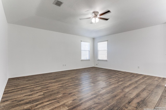 unfurnished room with dark wood finished floors, visible vents, baseboards, and ceiling fan