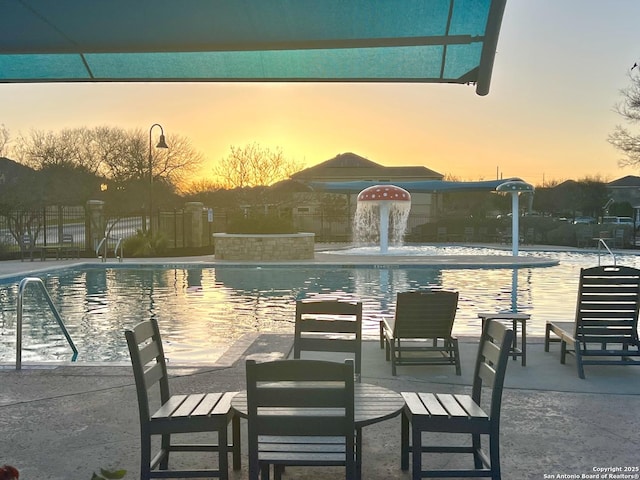 pool at dusk featuring a community pool, a patio, and fence