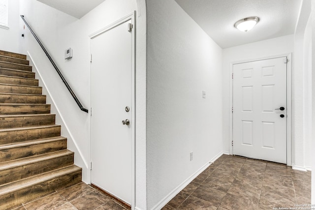 foyer featuring baseboards and stairs