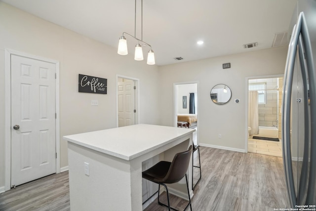 kitchen with visible vents, light wood finished floors, and freestanding refrigerator