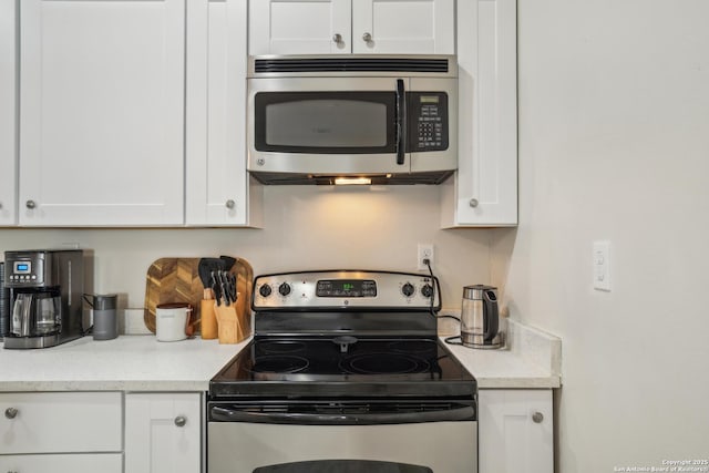 kitchen featuring stainless steel appliances, light stone countertops, and white cabinets