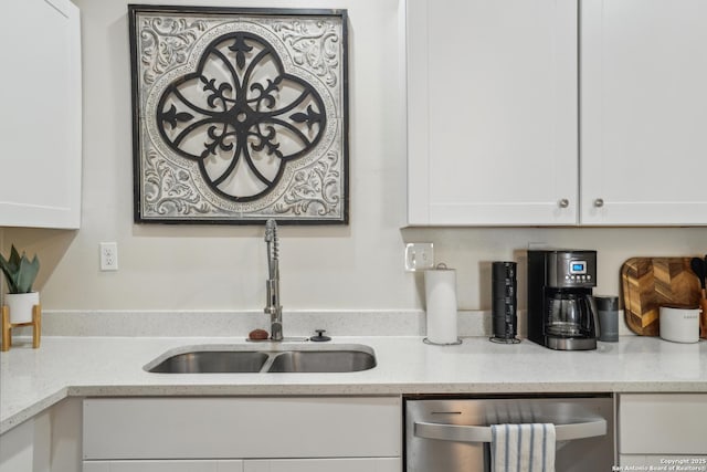 kitchen featuring dishwasher, white cabinets, light stone countertops, and a sink