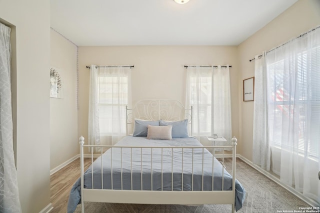 bedroom featuring multiple windows, wood finished floors, and baseboards