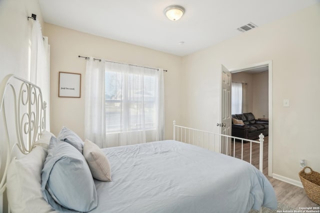 bedroom with visible vents, baseboards, and wood finished floors