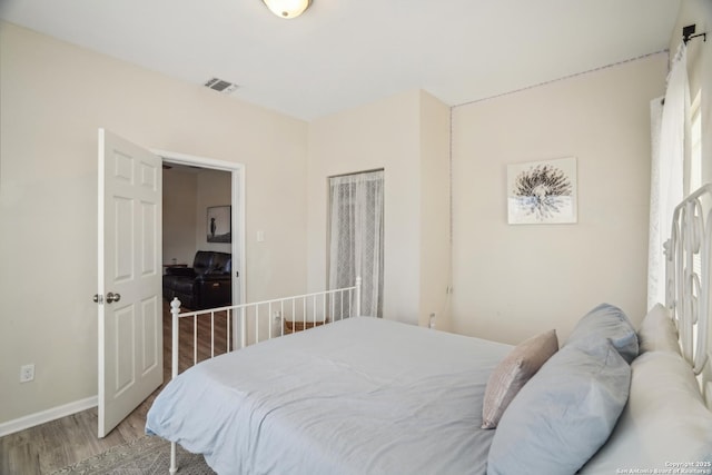 bedroom featuring visible vents, baseboards, and light wood finished floors