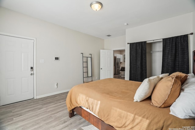 bedroom featuring visible vents, light wood-style flooring, freestanding refrigerator, and baseboards