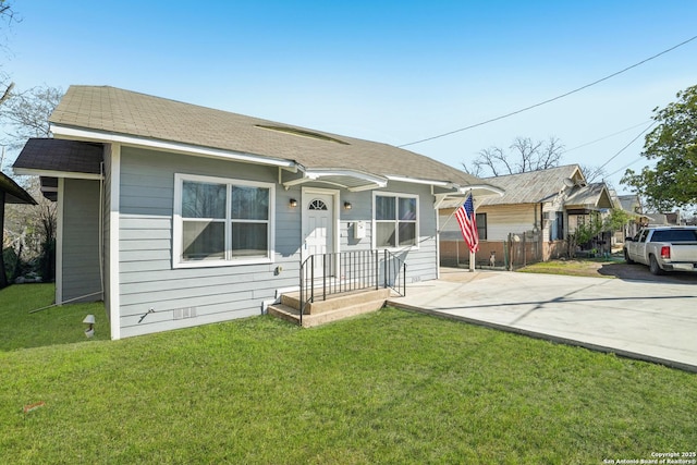 view of front of property featuring a front lawn, fence, driveway, and roof with shingles