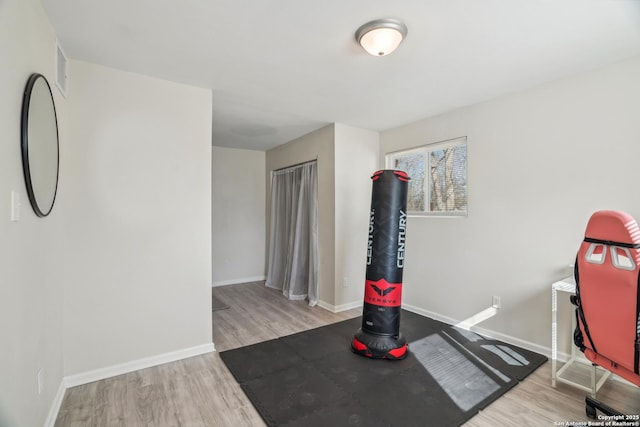 exercise room with wood finished floors and baseboards