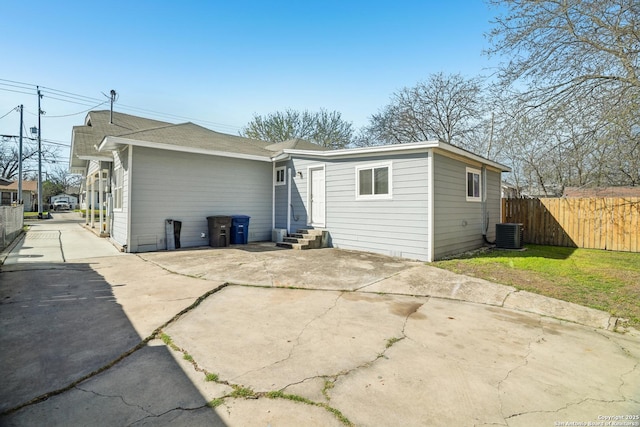 rear view of property with fence, central AC unit, and entry steps