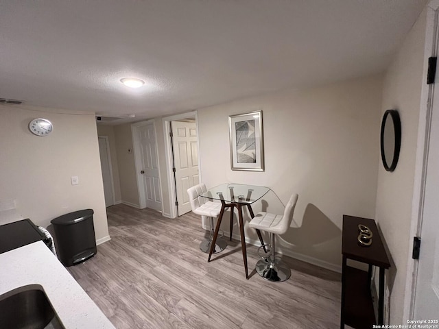 office space with visible vents, baseboards, a textured ceiling, and wood finished floors