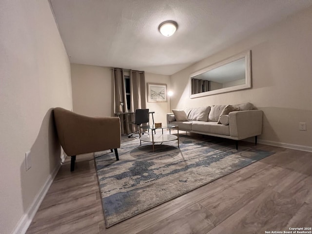 living room with wood finished floors, baseboards, and a textured ceiling