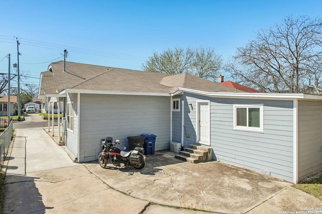 back of property with roof with shingles and entry steps