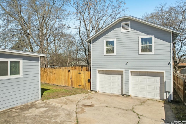 view of side of home with a garage, concrete driveway, and fence