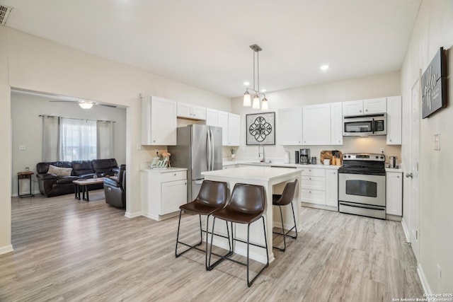 kitchen with white cabinetry, appliances with stainless steel finishes, a breakfast bar area, and light countertops