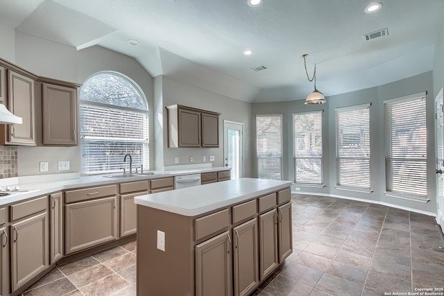 kitchen featuring white appliances, visible vents, a kitchen island, vaulted ceiling, and a sink