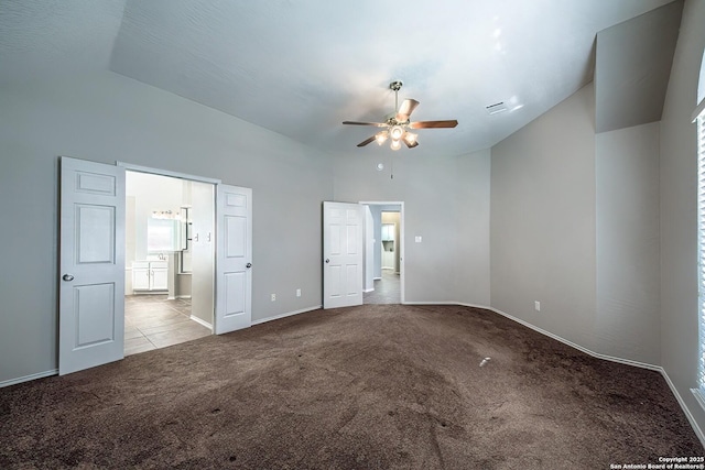 interior space with carpet floors, lofted ceiling, baseboards, and ensuite bath