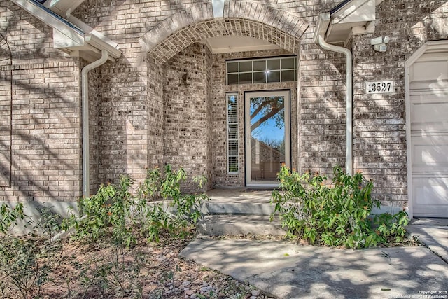 property entrance with a garage and brick siding