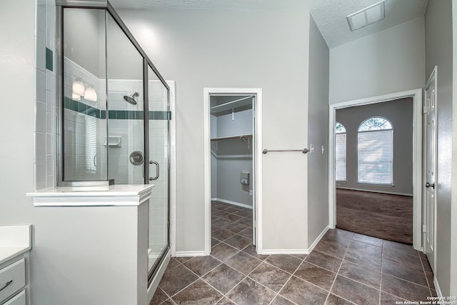 bathroom featuring vanity, visible vents, baseboards, a stall shower, and a walk in closet