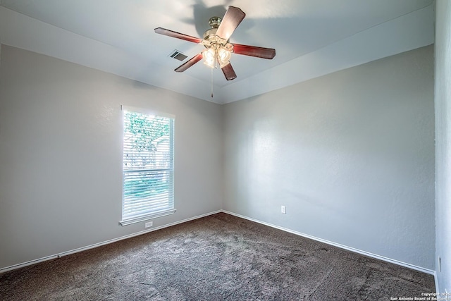 empty room with a ceiling fan, visible vents, dark carpet, and baseboards