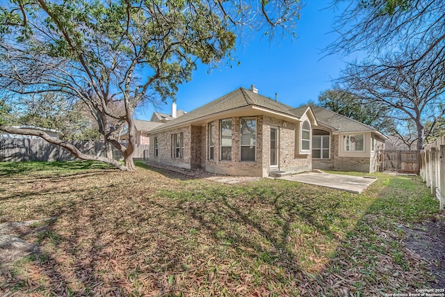 rear view of property featuring a yard, brick siding, a patio area, and a fenced backyard