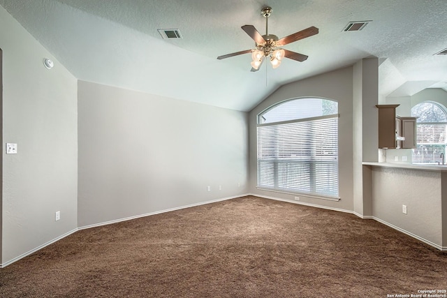 empty room featuring lofted ceiling, visible vents, ceiling fan, and carpet