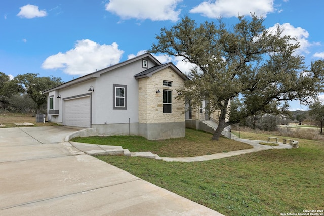 view of side of property featuring central AC unit, a garage, concrete driveway, stone siding, and a lawn