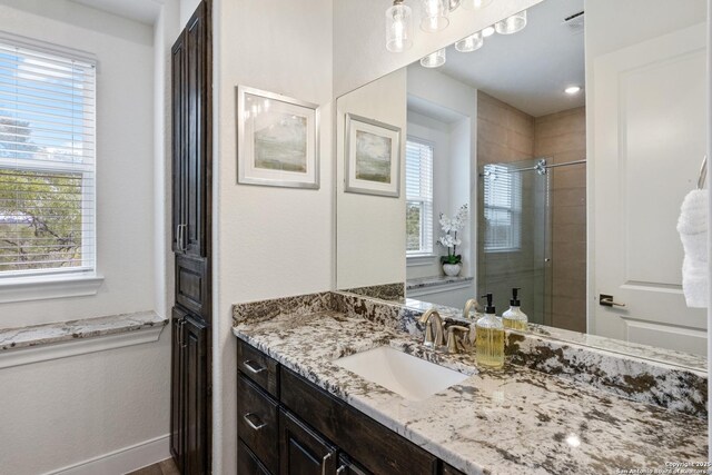 full bath featuring a stall shower, visible vents, vanity, and baseboards