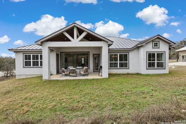 back of house featuring metal roof, a standing seam roof, a yard, a patio area, and stucco siding