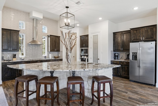 kitchen featuring stainless steel appliances, visible vents, dark wood-type flooring, a sink, and wall chimney exhaust hood