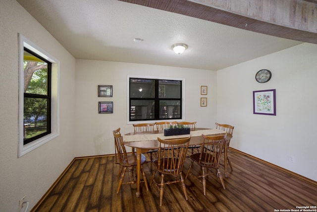 dining space featuring a textured ceiling, baseboards, and wood finished floors