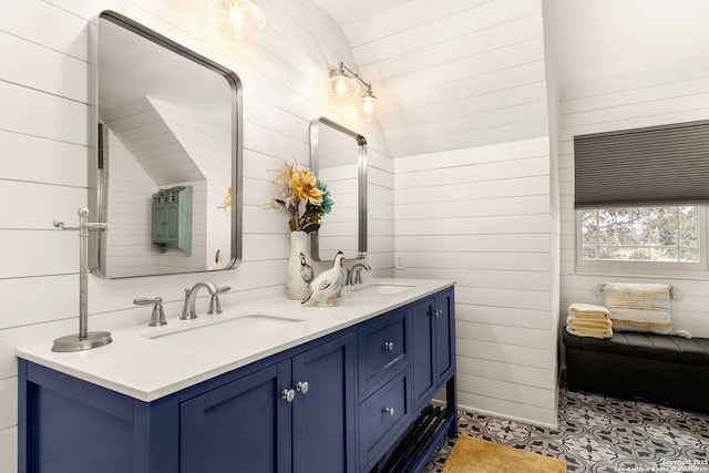 bathroom with double vanity, wood walls, and a sink