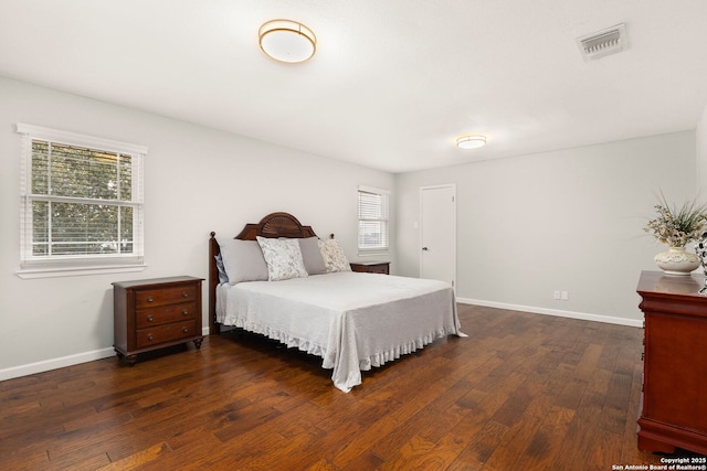 bedroom with hardwood / wood-style flooring, visible vents, and baseboards