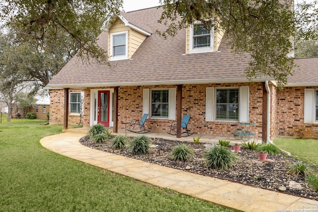 view of front of home featuring roof with shingles, a front lawn, and brick siding