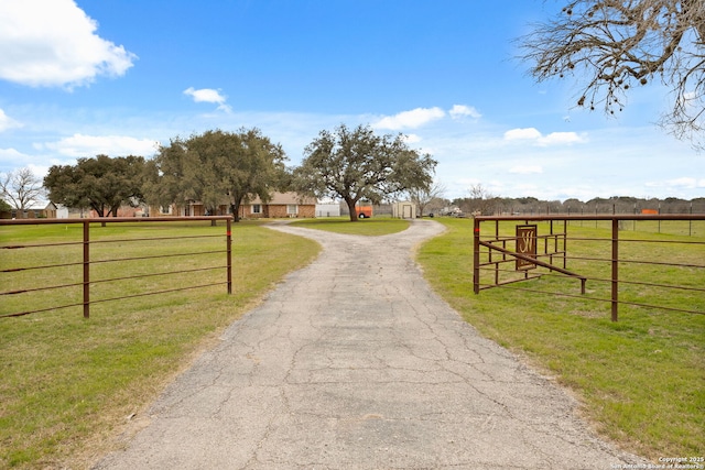 view of street with aphalt driveway, a rural view, and a gated entry