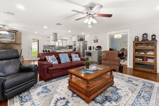 living area with ornamental molding, light wood-style flooring, and visible vents