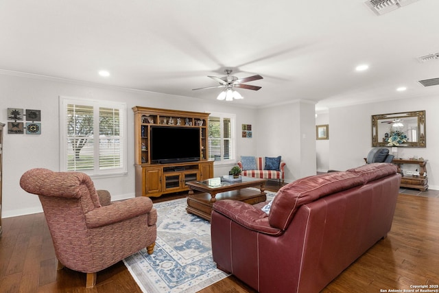 living room with ornamental molding, visible vents, baseboards, and wood finished floors