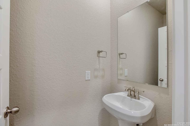 bathroom with a textured wall and a sink