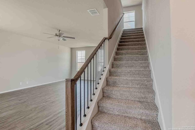 staircase with baseboards, ceiling fan, visible vents, and wood finished floors