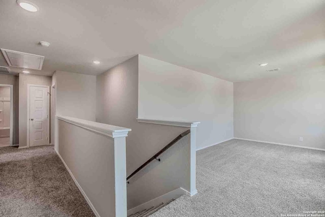 hall featuring attic access, baseboards, carpet flooring, and an upstairs landing