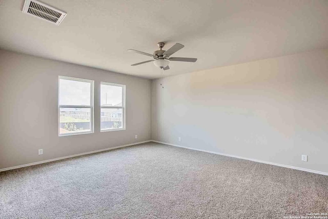 carpeted spare room with a ceiling fan, visible vents, and baseboards