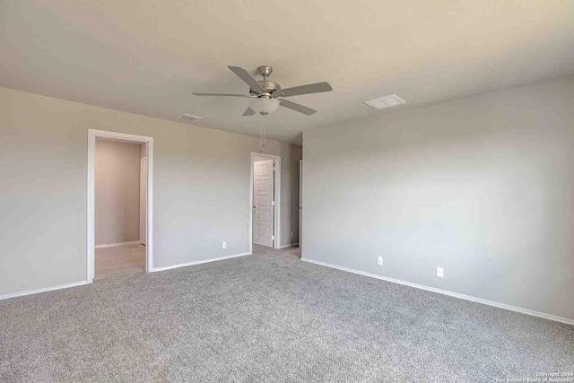 carpeted spare room featuring a ceiling fan, visible vents, and baseboards