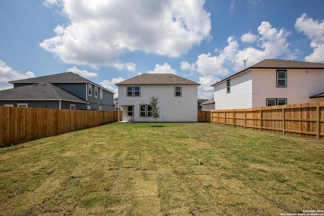 rear view of property with a fenced backyard and a yard