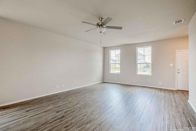 empty room featuring ceiling fan, wood finished floors, visible vents, and baseboards