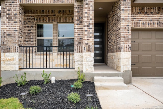 property entrance with an attached garage and brick siding