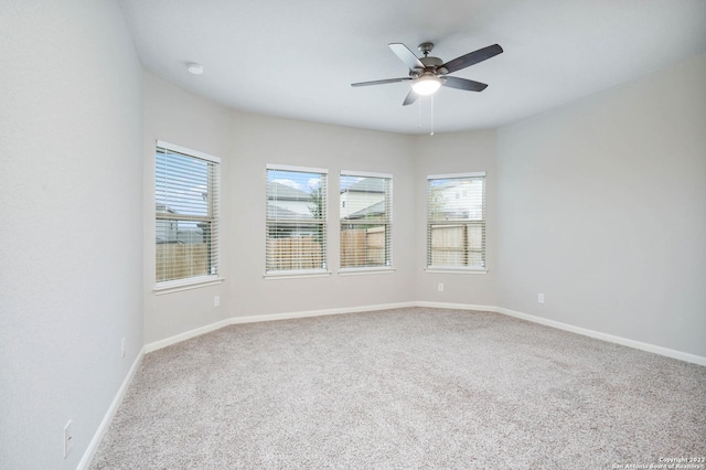 carpeted empty room featuring a ceiling fan and baseboards